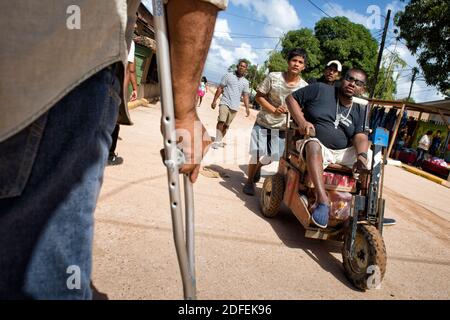 Persone disabili paralizzate da malattia da decompressione (DCS) a causa di intensa pesca di aragosta utilizzando metodi di immersione subacquea, utilizzando sedie a rotelle in legno fatte in casa. Puerto Lempira, Mosquitia, Honduras Foto Stock