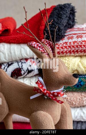 Un lotto di pullover e pullover diversi colori piegati in due pile e Deer Toy. Foto Stock