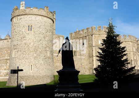 Silhouette della Statua della Regina Vittoria e albero di Natale di fronte alle mura del Castello di Windsor, Castle Hill, Windsor, Berkshire, Inghilterra, Regno Unito Foto Stock