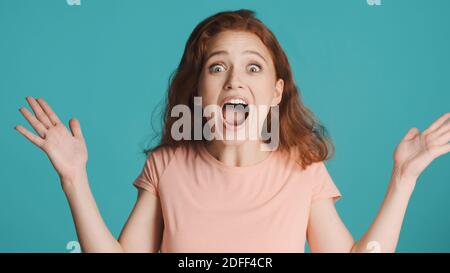 Attraente scioccata ragazza emozionale urlando e guardando stupito in macchina fotografica su sfondo colorato. Espressione di gioia Foto Stock