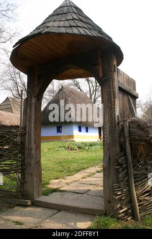 Il Museo del Villaggio, Bucarest, Romania. Autentica casa del 19 ° secolo dalla contea di Alba, con tetto di paglia. Cancello in legno intagliato in modo tradizionale. Foto Stock