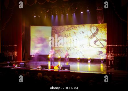 Texture offuscare scena luci multicolore e fumo in concerto con le sagome della gente. Sfondo per design, texture sfocata, attori sul palco. Foto Stock