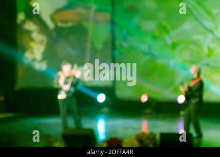 Texture offuscare scena luci multicolore e fumo in concerto con le sagome della gente. Sfondo per design, texture sfocata, attori sul palco. Foto Stock