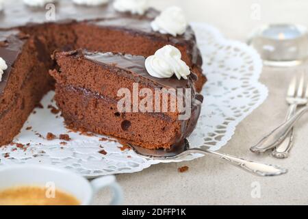 Deliziosa torta di cacao viennese con marmellata di ribes rosso e ricoperta di cioccolato fondente e crema, servita con caffè Foto Stock