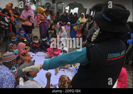 Una donna volontaria vista ha dato il punto di mente per i bambini che hanno colpito dall'eruzione del vulcano Sinabung durante ha ricevuto l'aiuto dai volontari della Fondazione al Kahfi come un'azione di aiuto caritativa per i residenti dei villaggi di Kuta Tengah, Berastepu e Gamber (Tiga Serangkai) Alla moschea di al-Jihad a Karo, Sumatra del Nord, Indonesia il 30 agosto 2020. In diverse notizie relative all'eruzione del vulcano Sinabung, umanamente alcuni volontari di al-Kahfi sono venuti a trattare la psicologia dei residenti, soprattutto per i bambini che vivono alla soglia di una zona di rischio di disastri geologici. Foto di Foto Stock