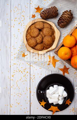 Accogliente still life invernale con tangerini, biscotti, coni di pino e una tazza di marshmallows su un tavolo di legno chiaro. Vista dall'alto, posiziona per il testo. Foto Stock