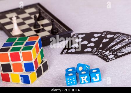 Foto di morsi blu da un gioco di mazza bugiardo, un cubo Rubik standard, carte che mostrano una scala di poker nero e mezzo scacchiera Foto Stock