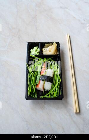 Take away Sushi Kani nigiri Surimi Crab con bastoncini di pollo in plastica nera piastra. Pronto a mangiare. Foto Stock