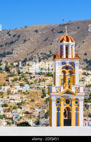 Il campanile della Chiesa dell'Annunciazione con vista verso la vecchia collina Horio, Isola di Symi, Dodecanese, Grecia Foto Stock