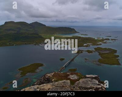 Bella vista panoramica aerea del piccolo villaggio Fredvang situato sull'isola di Moskenesøya, Lofoten, Norvegia con ponti stradali e montagne sulla costa. Foto Stock