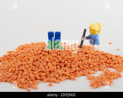 Parigi in Francia il 21 novembre 2020.na allestimento con due giocattoli. Una donna che attraversa il mucchio di lenticchie di corallo. Concetto intorno al lavoro e alla caduta. Foto Stock