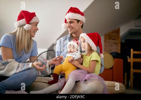 Giovani sposi che si divertono con i bambini la vigilia di Capodanno in un'atmosfera allegra a casa. Anno nuovo, concetto di famiglia, insieme, amore Foto Stock