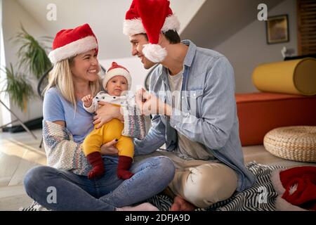 I giovani genitori in momenti piacevoli con il loro bambino alla vigilia di Capodanno in un'atmosfera allegra a casa. Anno nuovo, concetto di famiglia, insieme, amore Foto Stock