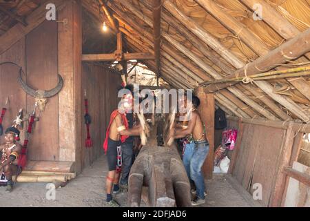 Messa a fuoco selettiva con movimento e movimento immagine di Naga uomini Hiting un ceppo di legno con legno al villaggio di Kisama in Nagaland India il 2 dicembre 2016 Foto Stock