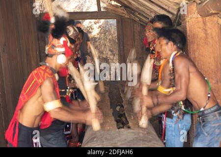 Messa a fuoco selettiva con movimento e movimento immagine di Naga uomini Hiting un ceppo di legno con legno al villaggio di Kisama in Nagaland India il 2 dicembre 2016 Foto Stock