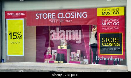 Una finestra di un negozio Debenhams a Stockport, Greater Manchester, Inghilterra, Regno Unito, mostra 'chiusura in corso', 'tutto deve andare' e '15% di sconto' poster. Il 1° dicembre 2020, Debenhams è andato in liquidazione, collassando nell'amministrazione e mettendo a rischio 12,000 posti di lavoro in 124 negozi britannici. Foto Stock