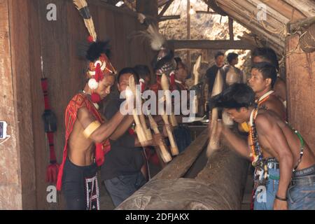 Messa a fuoco selettiva con movimento e movimento immagine di Naga uomini Hiting un ceppo di legno con legno al villaggio di Kisama in Nagaland India il 2 dicembre 2016 Foto Stock