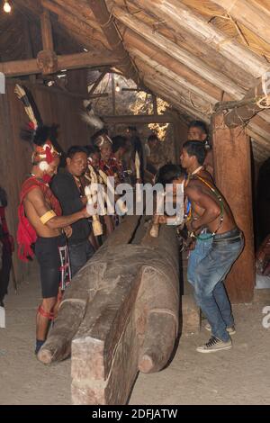 Messa a fuoco selettiva con movimento e movimento immagine di Naga uomini Hiting un ceppo di legno con legno al villaggio di Kisama in Nagaland India il 2 dicembre 2016 Foto Stock