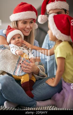 I giovani genitori in momenti piacevoli con i bambini in un'atmosfera familiare alla festa di Capodanno a casa. Anno nuovo, concetto di famiglia, insieme, amore Foto Stock