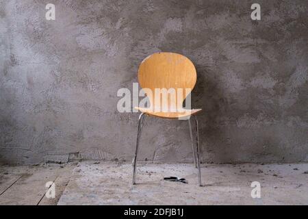 di fronte a una casa appena intonacata grigio muro stand una sedia gialla Foto Stock