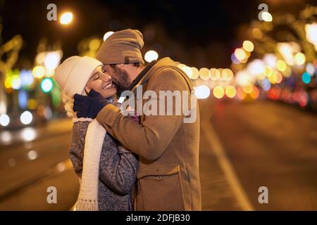Una giovane coppia che mostra emozioni in una passeggiata della città in una notte fredda. Relazione, insieme, Natale Foto Stock
