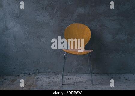 di fronte a una casa appena intonacata grigio muro stand una sedia gialla Foto Stock