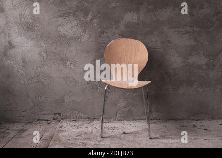 di fronte a una casa appena intonacata grigio muro stand una sedia gialla Foto Stock