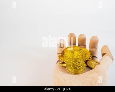 Una mano di legno sopra una pila di monete d'oro. Concetto di denaro e di investimento. Foto Stock