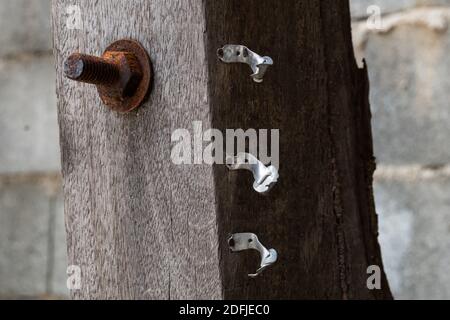 Vecchio palo in legno con vecchia pinza per cavi a parete in alluminio rotta Foto Stock