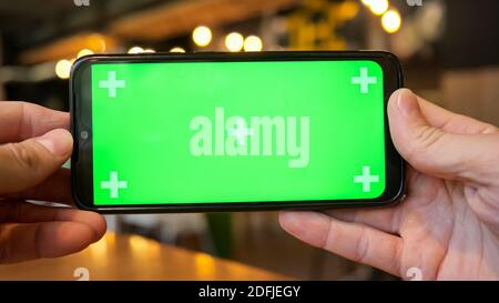Mani maschili che tengono un telefono con uno schermo verde. Foto Stock