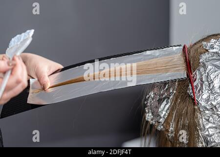 Lo stylist dei capelli fa il bouffant sui trefoli sottili ed applica sbianca polvere usando shatush Foto Stock