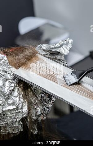 Lo stylist dei capelli fa il bouffant sui trefoli sottili ed applica la polvere sbiancante usando la tecnica dello shatush. Foto Stock