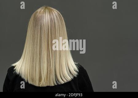 Modello biondo con capelli lisci, guarda da dietro. Risultato di schiarimento dei capelli. Spazio di copia Foto Stock