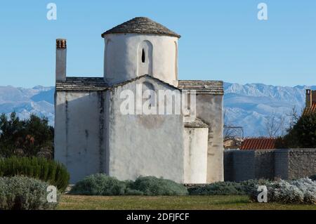 Nin, Croazia - famoso monumento, la chiesa di Santa Croce e Velebit montagne sullo sfondo; conservato architettura pre-romanica Foto Stock