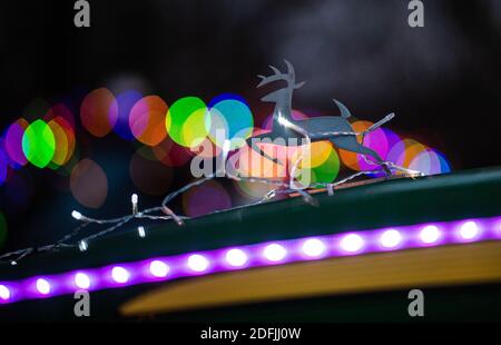 05 dicembre 2020, Renania Settentrionale-Vestfalia, Lüdenscheid: Un vago a forma di emblema del produttore di macchine agricole John Deere è decorato con una catena di luci su un trattore vicino al villaggio per bambini SOS. Gli agricoltori vogliono utilizzare centinaia di trattori illuminati di Natale in molte parti del NRW per fornire un po' di speranza nella pandemia. La campagna sulla vigilia di San Nicola è sotto il motto 'UNA scintilla di speranza'. Foto: Jonas Güttler/dpa Foto Stock