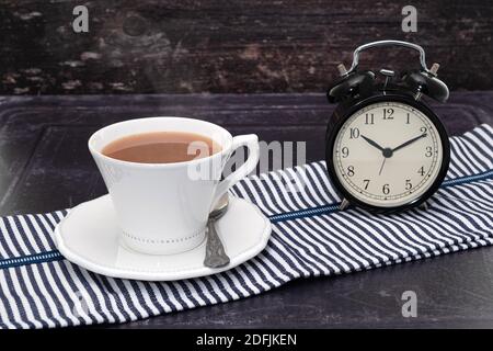 Una bevanda calda di tè o caffè con un orologio - concetto di pausa tè o caffè Foto Stock