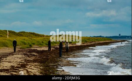 Persone che camminano lungo una spiaggia nella regione baltica in un giorno d'autunno tempestoso. Foto Stock