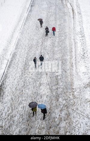 Vista dall'alto verso il basso su persone che camminano lungo una strada innevata. Foto Stock