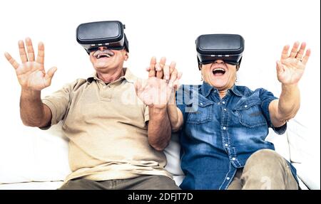 Una coppia matura che si diverte insieme a una cuffia per la realtà virtuale Seduto sul divano - felici pensionati che usano la realtà virtuale moderna occhiali da goggle Foto Stock