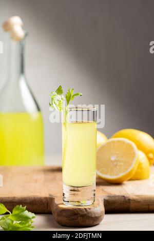 Liquore tradizionale italiano Limoncello. Bottiglia di vetro con liquore fatto in casa al limoncello, piatto con limoni e sedano. Foto Stock