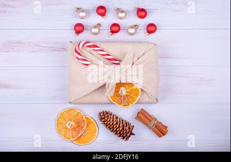 Regalo di Natale in confezione furoshiki. Zero rifiuti, vacanze di natale ecologiche, arredamento concetto. Tradizioni giapponesi. Vista dall'alto, messa a fuoco selettiva. Foto Stock