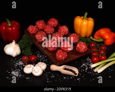 palline di topi di manzo su un asse di legno con ingredienti per Bolognese Foto Stock