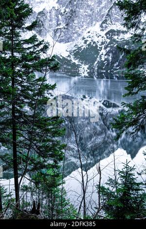 Belle montagne coperte di neve si riflettono in lago, periodo invernale. Pinete, pallette verdi, blu e bianche. Paesaggio nord grave. Foto Stock