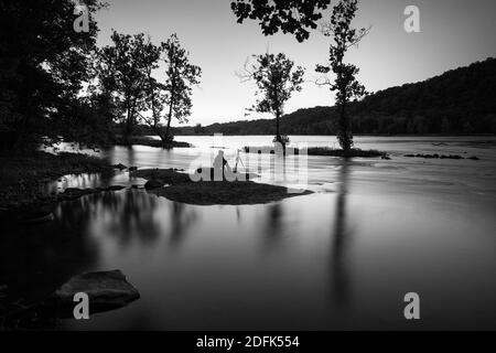 Un fotografo si siede su un'isola di notte e fotografa la natura. Foto Stock