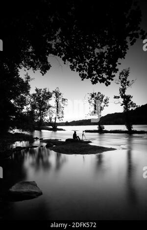 Un fotografo si siede su un'isola di notte e fotografa la natura. Foto Stock