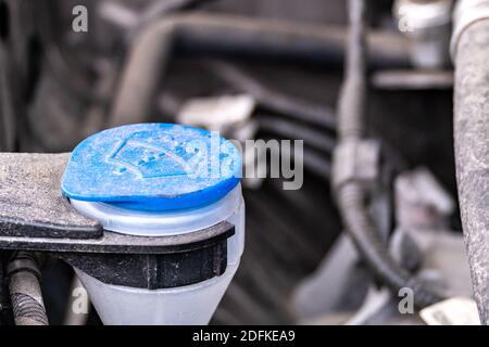 Vista laterale ravvicinata di un tappo in plastica blu che copre un tubo per il riempimento di un serbatoio del liquido dei tergicristalli. Foto Stock