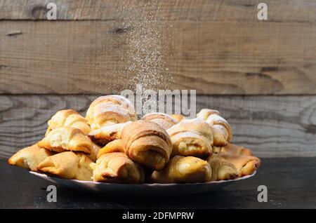 Biscotti fatti in casa sotto forma di bagel con marmellata di ripieno cosparso di zucchero in polvere su uno sfondo di legno. Messa a fuoco selettiva. Foto Stock