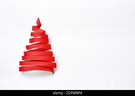 Albero di Natale fatto dal nastro rosso su sfondo bianco. Spazio di copia Foto Stock