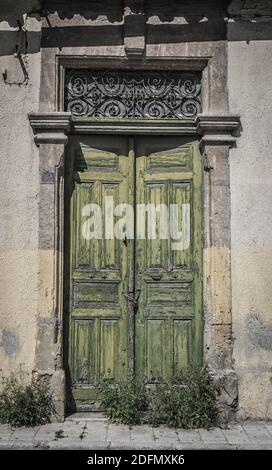 Vecchia porta a Cipro con vernice verde peeling e sovra-crescita da erbacce così inutilizzate Foto Stock