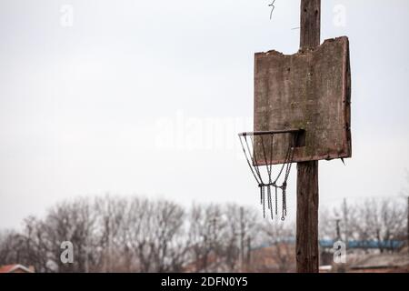 Vecchio, mezzo distrutto, marcio basketball backboard, in un decadente parco giochi di sport, in piedi durante un freddo inverno. Immagine di un vecchio backb della sfera del cesto Foto Stock